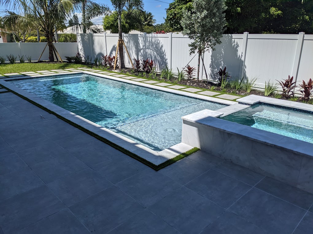Modern rectangular pool with raised marble spa and paver deck