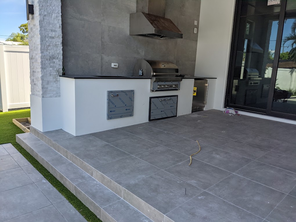 Covered outdoor kitchen with built-in grill and stone accent wall