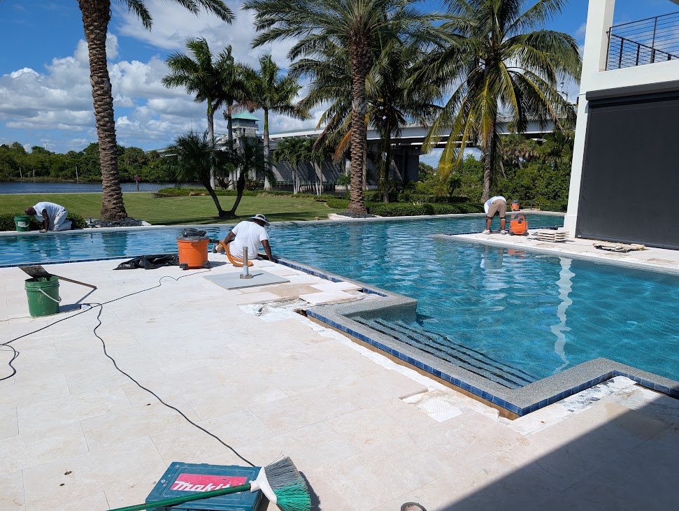 Waterfront pool remodel in progress with new tile and coping